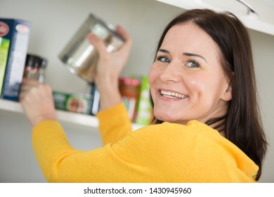 Happy Woman Looking In Empty Food Cupboards