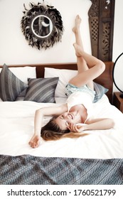 Happy Woman Lying On The Bed With Raised Legs Up