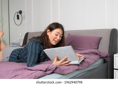 Happy woman lying on a bed. she watches photo album or reading a book. High quality photo - Shutterstock ID 1962940798