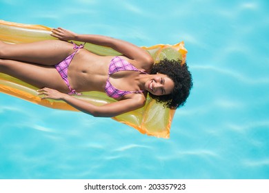 Happy Woman Lying On Lilo In Swimming Pool On A Sunny Day