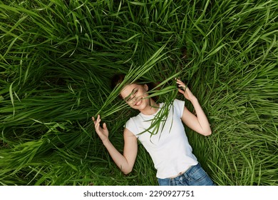 happy woman lying in tall grass biting leaves - Powered by Shutterstock