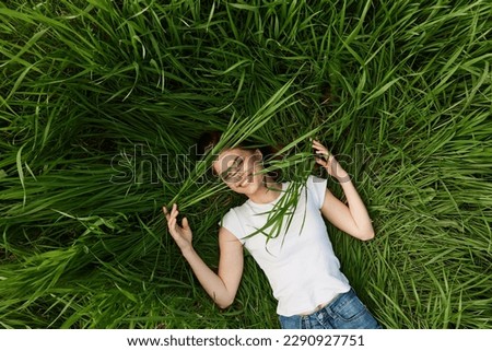 happy woman lying in tall grass biting leaves