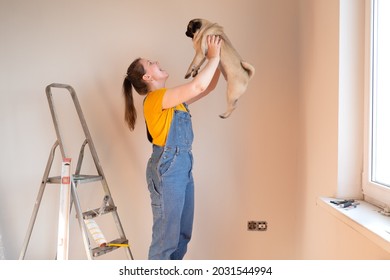 Happy Woman Makes Repairs In Her Apartment With Her Funny Pug Dog. Happiness In Anticipation Of A New Home And Moving. Independent Single Life With A Pet 