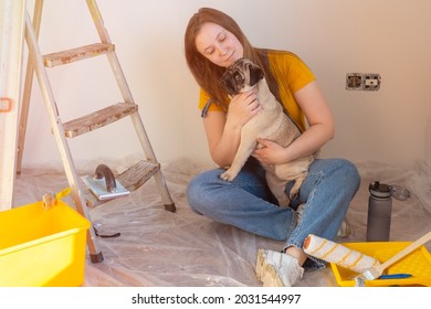 Happy Woman Makes Repairs In Her Apartment With Her Funny Pug Dog. Happiness In Anticipation Of A New Home And Moving. Independent Single Life With A Pet 