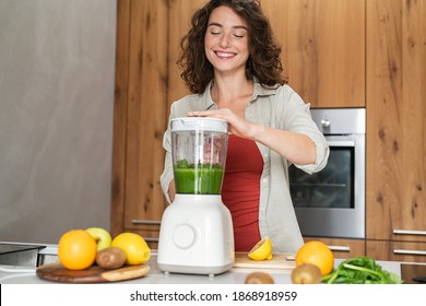 Happy woman making healthy fruit smoothies. Smiling young woman making healthy drink using blender with fresh vegetables. Girl making juice using juicer machine: wellness, diet and healthy eating. - Powered by Shutterstock