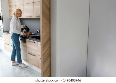 Happy Woman Is Making Tea In The Kitchen Stock Photo