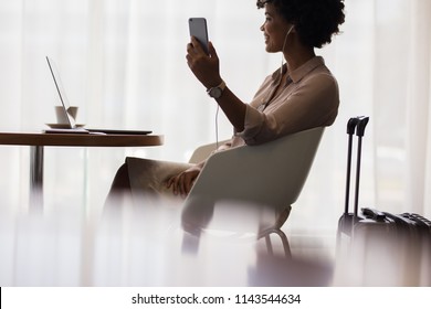 Happy Woman Making Video Call From Mobile Phone While Sitting At Airport Lounge. Business Woman Waiting For Flight At Airport And Using Smart Phone.