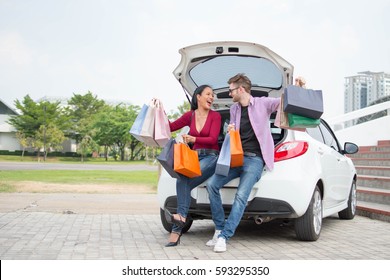 Happy Woman With A Man  After Shopping In The Mall And Arranging Shopping Bags In Car 