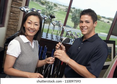 Happy Woman With Man Selecting Golf Club In Store