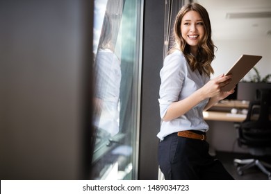 Happy Woman Manager Holding Tablet And Standing In Modern Office