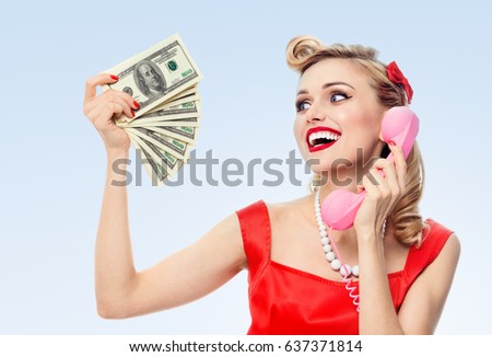 Happy woman with money, talking on phone, dressed in pin-up style dress in polka dot, on blue background. Caucasian blond model posing in retro fashion and vintage concept studio shoot.