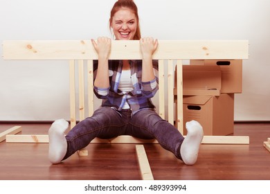 Happy woman moving in having fun assembling furniture at new home. Crazy young girl arranging apartment house interior and unpacking boxes. DIY.