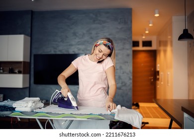 A Happy Woman Multitasking. A Woman Doing Laundry And Talking On The Phone.