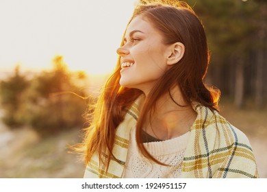 Happy woman near the forest in nature in warm clothes at sunset