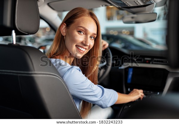 Happy woman\
new car owner sitting in driver\
seat