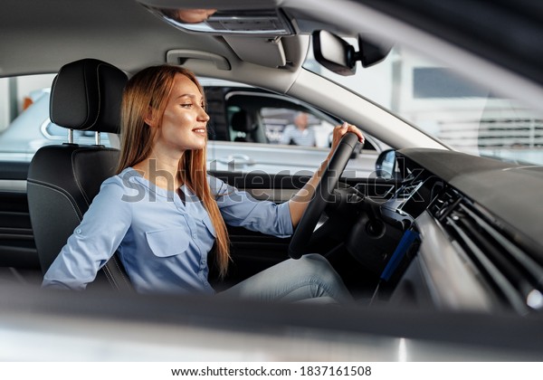 Happy woman\
new car owner sitting in driver\
seat