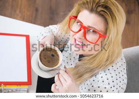 Happy woman at office drinking hot coffee or tea enjoying her break time during work. Job relax.