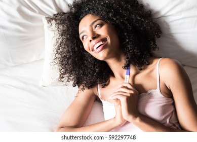 Happy Woman On Bed With A Pregnancy Test 