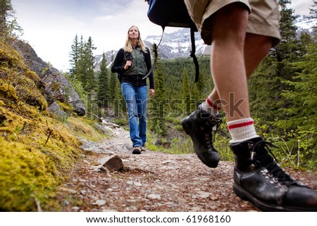 A happy woman on a mountain trail with mountains in the background