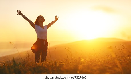 Happy woman   on the sunset in nature in summer with open hands