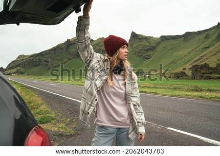 Happy woman on a vacations, closed trunk of her car while looking at the nature