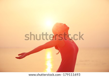 happy woman open arms under the sunrise at sea 