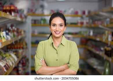 Happy Woman Owner With Arms Crossed At Grocery Aisle Of Supermarket