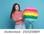 Happy woman with pinata on light blue background