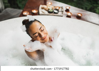 Happy Woman Playing With Foam In Big Bath With Bubbles. Relaxation In Spa