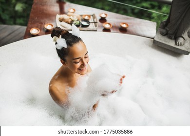 Happy Woman Playing With Foam In Big Bath With Bubbles. Relaxation In Spa