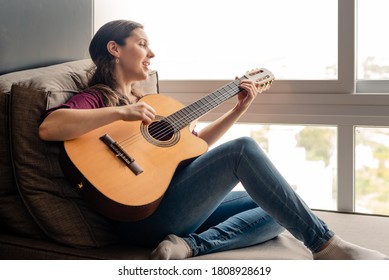 Happy woman playing guitar and singing - Shutterstock ID 1808928619