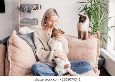 Happy woman playing with her dog on the couch at home. Dog licking middle aged woman in the living room - Powered by Shutterstock