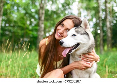 Happy Woman  Playing With Her Dog In The Yard Of The House In Spring. Siberian Husky.