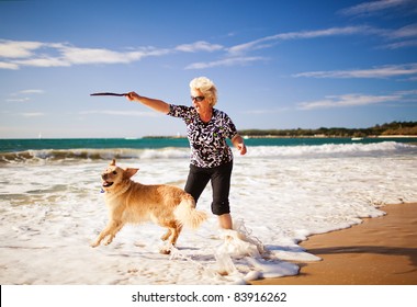 Happy woman playing on the beach with golden retriever - Powered by Shutterstock