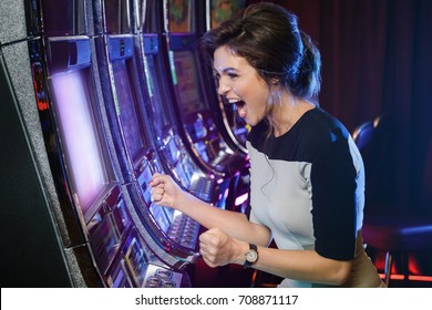 Happy woman playing slot machines in the casino