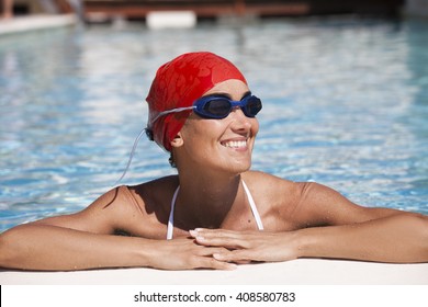 happy woman in a pool with bathing cap and swimming goggles
