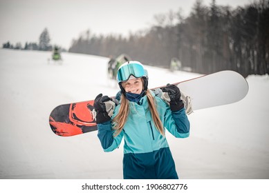 Happy  woman posing with her snowboard getting ready to go riding