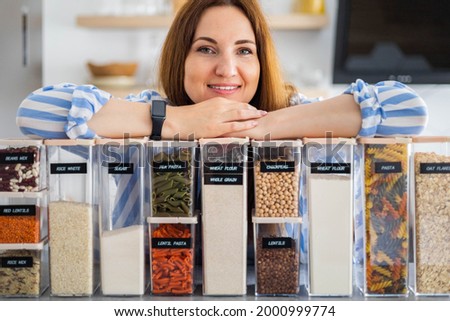 Happy woman professional space organizer smiling posing with plastic case boxes for comfortable product storage. Cute female enjoying healthy food organization, placing and sorting and kitchen