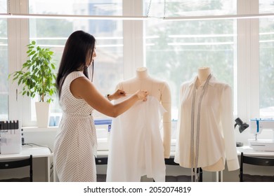 Happy woman professional tailor trying tissue pattern on mannequin working at sewing studio. Smiling female seamstress enjoy hobby at sew workshop creating fashion clothes. Dressmaker business owner