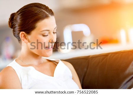 Happy woman reading a magazine sitting on a sofa