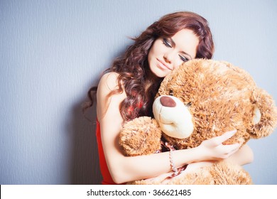Happy woman received a teddy bear. Blue background. Her beautiful eyes looking at camera. Concept of holiday, birthday, World Women's Day or Valentine's Day, 8 March. Copy space