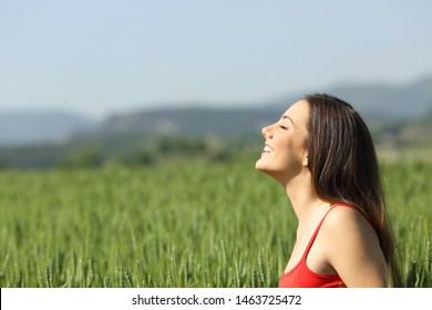 Happy woman in red breathing fresh air in a green field a sunny day