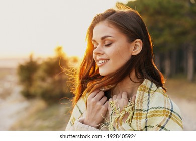 glückliche Frau mit rotem Haar bei Sonnenuntergang in der Nähe des Waldes