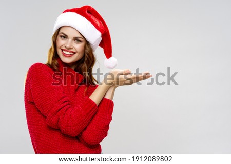 happy woman in red santa claus hat shows with hands to the side Copy Space