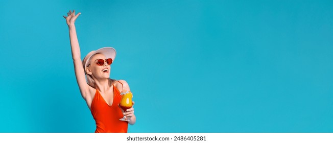 Happy woman in a red swimsuit and a white sunhat, with her arm raised in the air, holding a cocktail in her other hand. She is looking to the side with a big smile on her face, copy space - Powered by Shutterstock