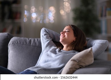 Happy Woman Relaxing With Arms On Head Sitting On A Couch In The Night At Home