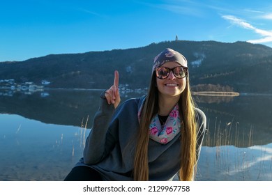 Happy woman relaxing at beautiful Woerthersee in Poertschach, Carinthia, Austria. Scenic lake landscape surrounded by Alps. Serenity. View on Pyramidenkogel. Fresh and clean air.Reflection,Lake Woerth