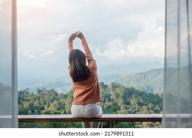 Happy woman relaxing and looking mountain view at countryside home or homestay in the morning. Vacation, blogger, SoloTravel, journey, trip and relaxing concept