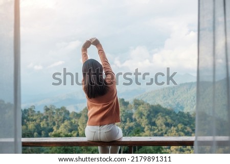 Happy woman relaxing and looking mountain view at countryside home or homestay in the morning. Vacation, blogger, SoloTravel, journey, trip and relaxing concept