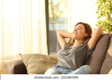 Happy woman resting comfortably sitting on a couch in the living room at home